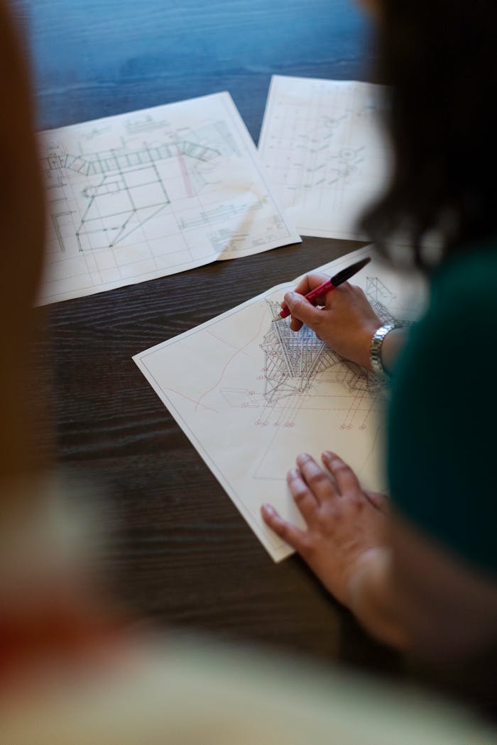 Female engineer working on detailed architectural blueprints on a wooden desk.